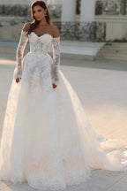 Robe de mariée blanche longue en dentelle, coupe trapèze, épaules dénudées et manches longues, ravissante.