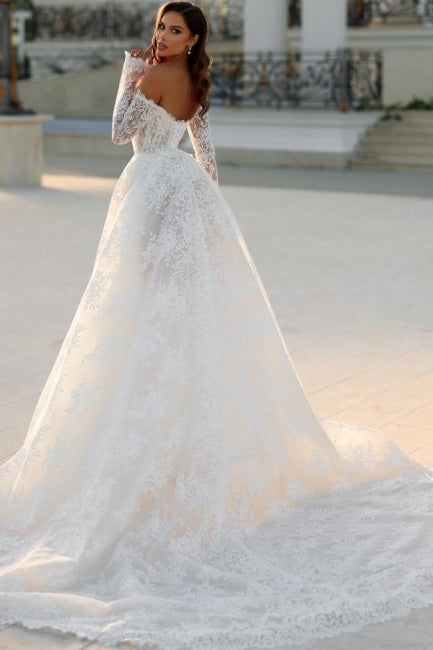 Robe de mariée blanche longue en dentelle, coupe trapèze, épaules dénudées et manches longues, ravissante.