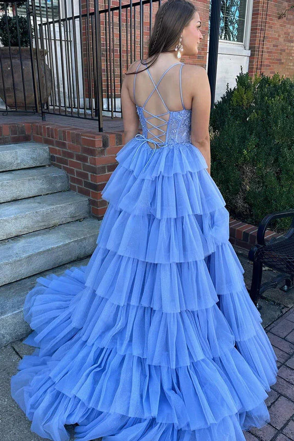 Robe de bal bleue à bretelles spaghetti, coupe trapèze, corset et appliques à volants.