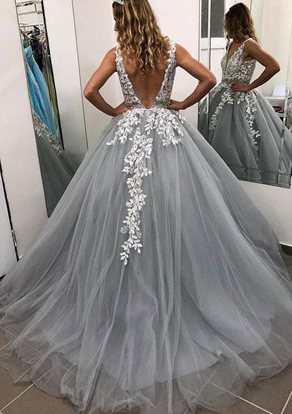 Robe de bal longue sans manches en tulle, arrivant au sol, ornée de dentelle et de perles appliquées.