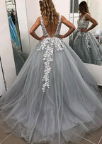 Robe de bal longue sans manches en tulle, arrivant au sol, ornée de dentelle et de perles appliquées.