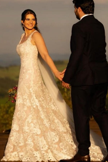 Magnifique robe de mariée longue ivoire en dentelle, coupe trapèze, sans manches, ornée d'appliqués.