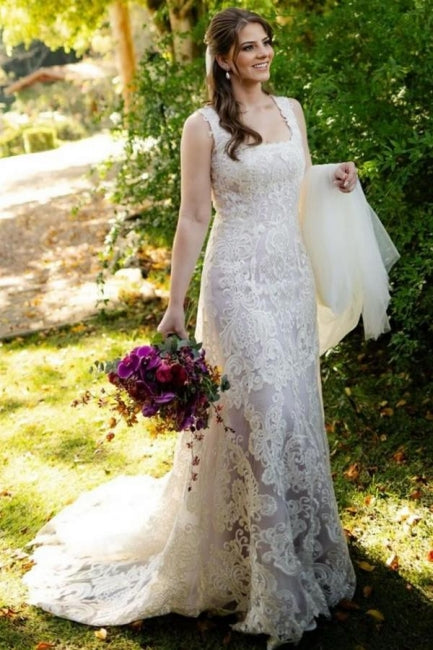 Magnifique robe de mariée longue ivoire en dentelle, coupe trapèze, sans manches, ornée d'appliqués.