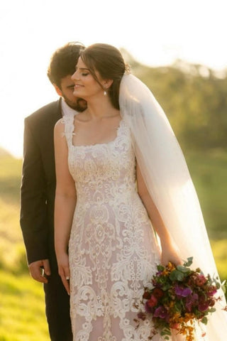 Magnifique robe de mariée longue ivoire en dentelle, coupe trapèze, sans manches, ornée d'appliqués.