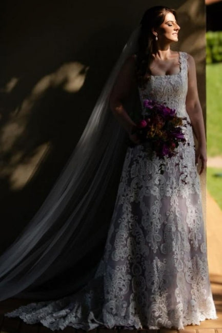 Magnifique robe de mariée longue ivoire en dentelle, coupe trapèze, sans manches, ornée d'appliqués.