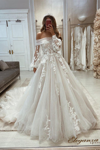 Precioso vestido de novia de corte A, hombros descubiertos, apliques, mangas largas y encaje.