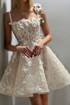 Magnifique robe de mariée courte ivoire sans manches, coupe trapèze, en tulle et dentelle, à fines bretelles spaghetti et ornée d'appliqués.