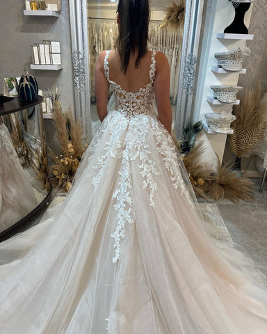 Magnifique robe de mariée longue sans manches à bretelles, coupe trapèze, en dentelle et fente.