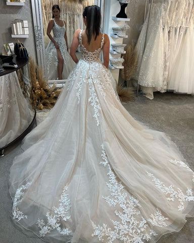 Magnifique robe de mariée longue sans manches à bretelles, coupe trapèze, en dentelle et fente.