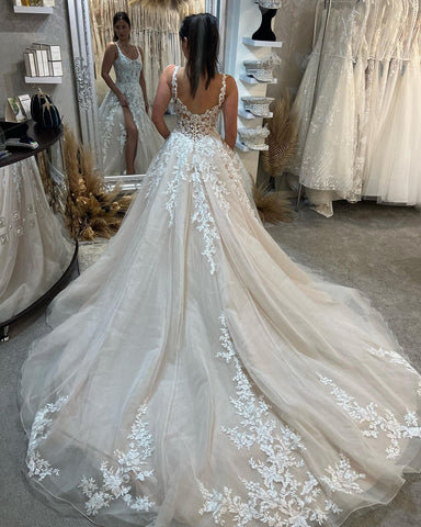 Magnifique robe de mariée longue sans manches à bretelles, coupe trapèze, en dentelle et fente.