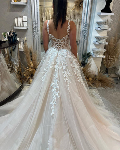Magnifique robe de mariée longue sans manches à bretelles, coupe trapèze, en dentelle et fente.