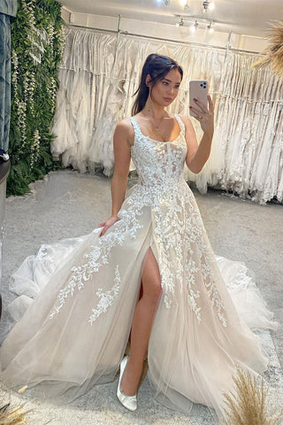 Magnifique robe de mariée longue sans manches à bretelles, coupe trapèze, en dentelle et fente.