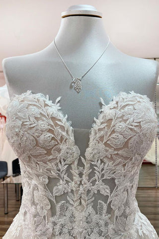 Magnifique robe de mariée longue en tulle ivoire, sans bretelles, de coupe trapèze, ornée d'appliqués de dentelle.