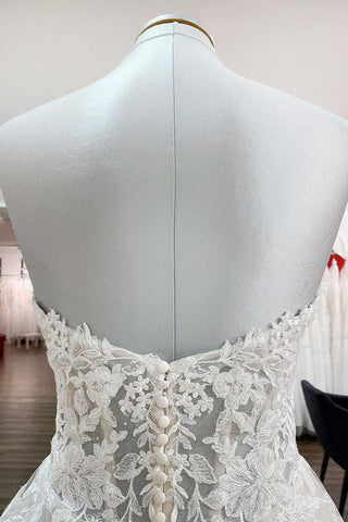 Magnifique robe de mariée longue en tulle ivoire, sans bretelles, de coupe trapèze, ornée d'appliqués de dentelle.