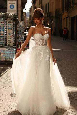 Magnifique robe de mariée longue ivoire en tulle et dentelle, coupe trapèze, bretelles spaghetti et dentelle.