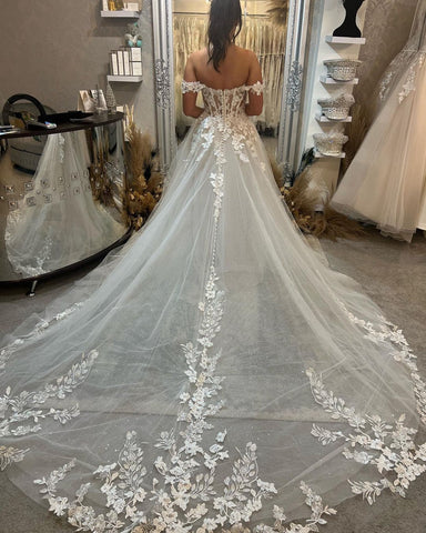 Magnifique robe de mariée longue à épaules dénudées, coupe trapèze, ornée d'appliqués et d'une traîne.