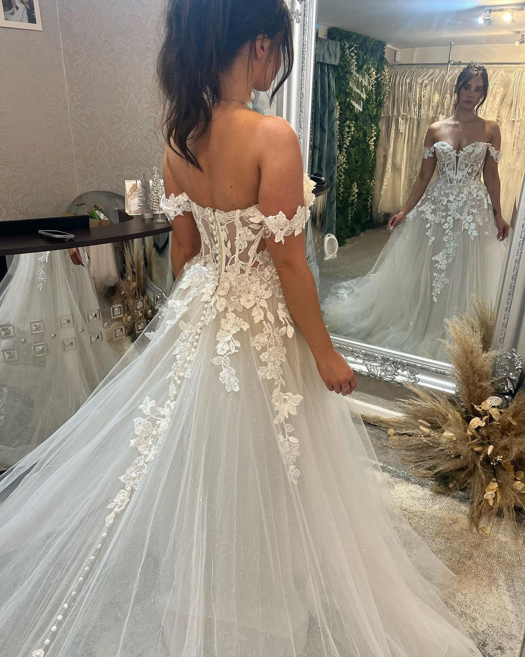 Magnifique robe de mariée longue à épaules dénudées, coupe trapèze, ornée d'appliqués et d'une traîne.