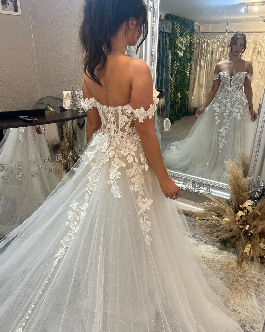 Magnifique robe de mariée longue à épaules dénudées, coupe trapèze, ornée d'appliqués et d'une traîne.