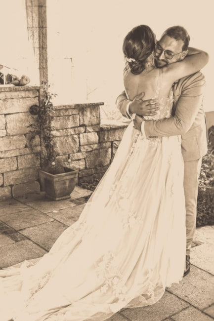 Magnifique robe de mariée blanche longue, coupe trapèze, col en V, sans manches, ornée de dentelle.