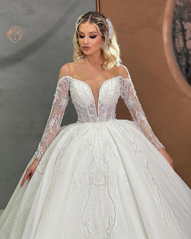Precioso vestido de novia de corte princesa con escote corazón, mangas largas y pedrería.