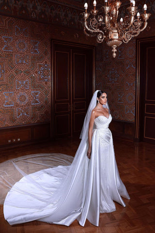 Magnifique robe de mariée blanche sans manches à décolleté cœur ornée de perles et traîne amovible.