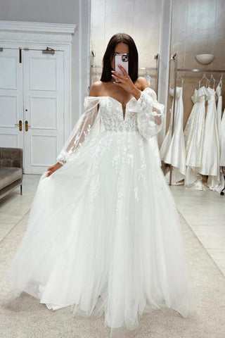 Robe de mariée bohème blanche longue en dentelle, coupe trapèze, épaules dénudées et manches longues