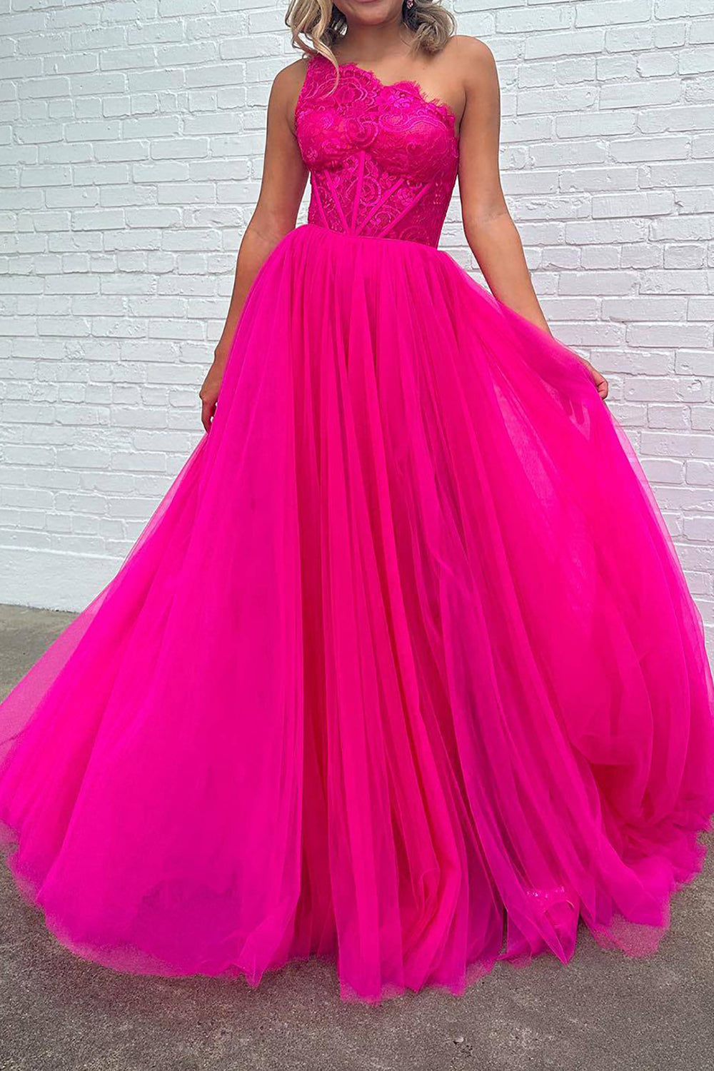 Vestido de fiesta fucsia de corte A, corte asimétrico, con corsé y abertura frontal.