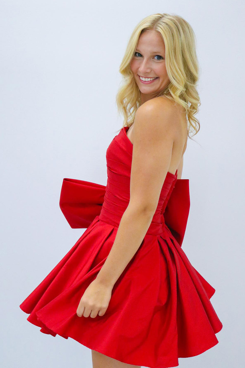 Vestido corto negro de corte recto y sin tirantes, ideal para fiestas de bienvenida, con lazo.