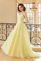 Magnifique robe de bal longue jaune à bretelles spaghetti et coupe trapèze, ornée d'appliqués.