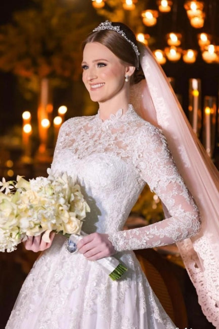 Robe de mariée blanche charmante, coupe trapèze, col montant, manches longues, en dentelle et ornée d'appliqués