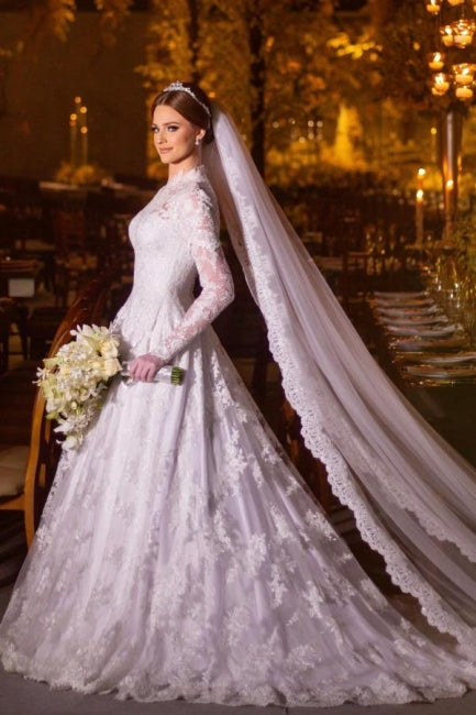 Robe de mariée blanche charmante, coupe trapèze, col montant, manches longues, en dentelle et ornée d'appliqués