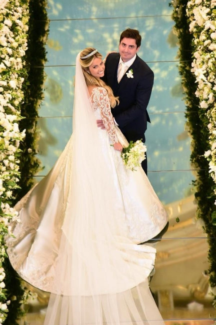 Robe de mariée blanche charmante, coupe trapèze, décolleté cœur, manches longues, en dentelle et ornée d'appliqués