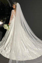 Robe de mariée blanche charmante, coupe trapèze, décolleté cœur, manches longues, en dentelle et ornée d'appliqués