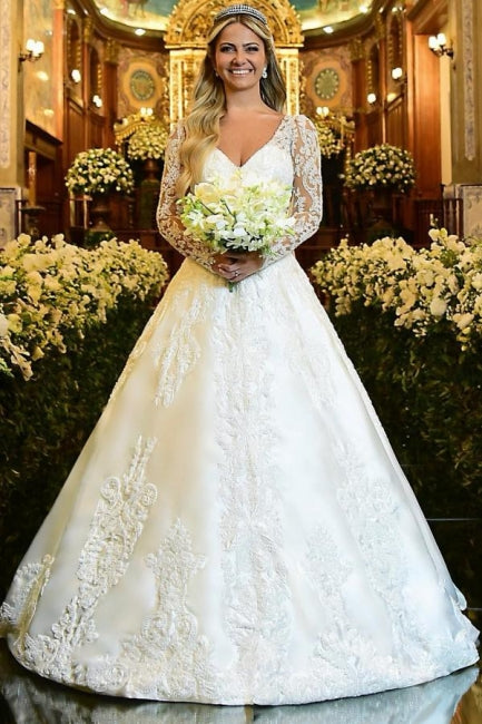 Robe de mariée blanche charmante, coupe trapèze, décolleté cœur, manches longues, en dentelle et ornée d'appliqués