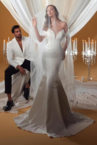 Encantador vestido de novia color marfil, de satén, corte columna, sin mangas, con hombros descubiertos y detalles de pedrería.