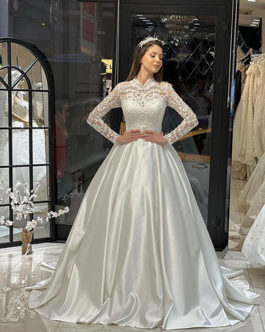 Robe de mariée trapèze en satin, charmante, longue jusqu'au sol, manches longues, col rond, ornée de volants.