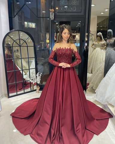 Robe de mariée charmante en satin, coupe trapèze, sans bretelles, manches longues et volants, longueur au sol.