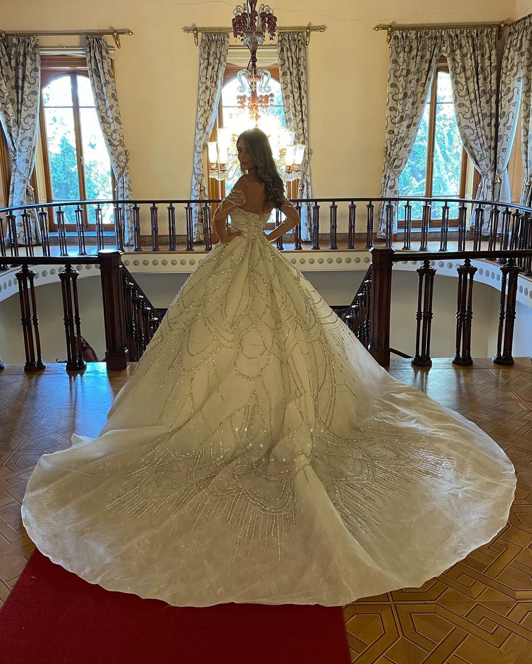 Robe de mariée charmante en dentelle, longue jusqu'au sol, décolleté cœur, manches longues et coupe trapèze, ornée de fleurs.
