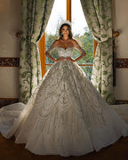 Robe de mariée charmante en dentelle, longue jusqu'au sol, décolleté cœur, manches longues et coupe trapèze, ornée de fleurs.