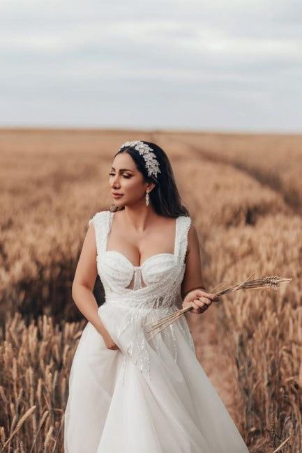 Robe de mariée blanche longue et charmante, coupe trapèze, sans manches, en tulle et dentelle.