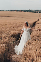 Robe de mariée blanche longue et charmante, coupe trapèze, sans manches, en tulle et dentelle.