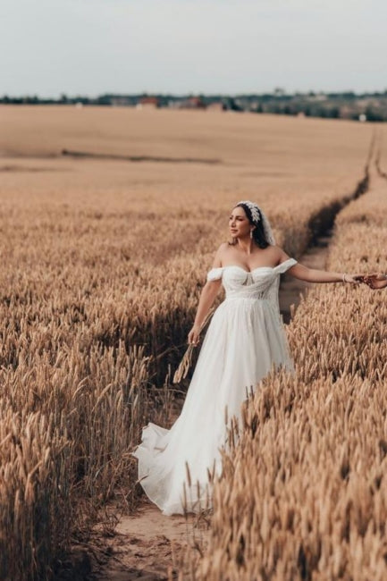 Robe de mariée blanche longue et charmante, coupe trapèze, sans manches, en tulle et dentelle.