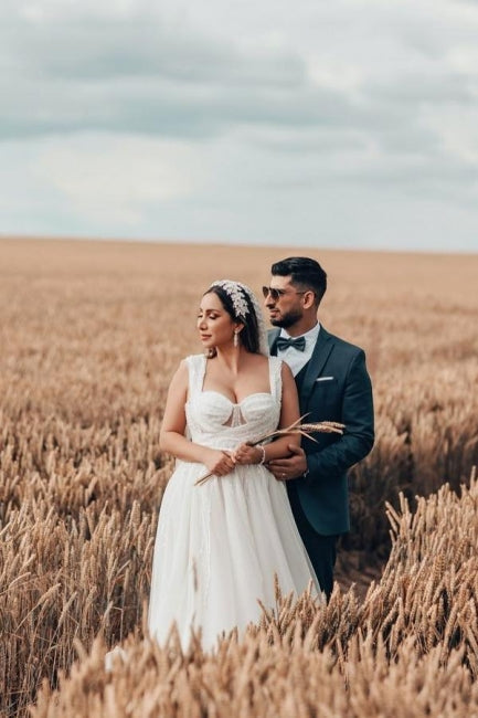 Robe de mariée blanche longue et charmante, coupe trapèze, sans manches, en tulle et dentelle.