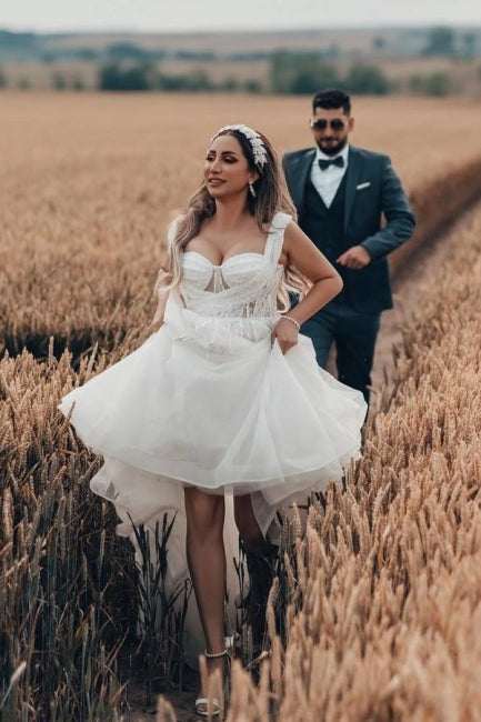 Robe de mariée blanche longue et charmante, coupe trapèze, sans manches, en tulle et dentelle.