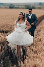 Robe de mariée blanche longue et charmante, coupe trapèze, sans manches, en tulle et dentelle.