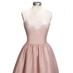Robe de bal courte dorée sans manches avec appliques, coupe asymétrique et décolleté cœur en dentelle.