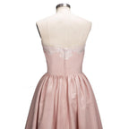 Robe de bal courte dorée sans manches avec appliques, coupe asymétrique et décolleté cœur en dentelle.