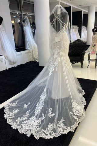 Encantador vestido de novia de encaje con tirantes finos y escote corazón, con cola de capilla.