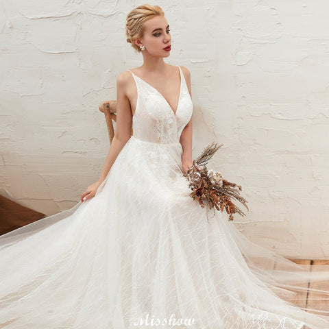 Elegante vestido de novia blanco de tul con escote en V profundo, espalda descubierta y cola de corte.