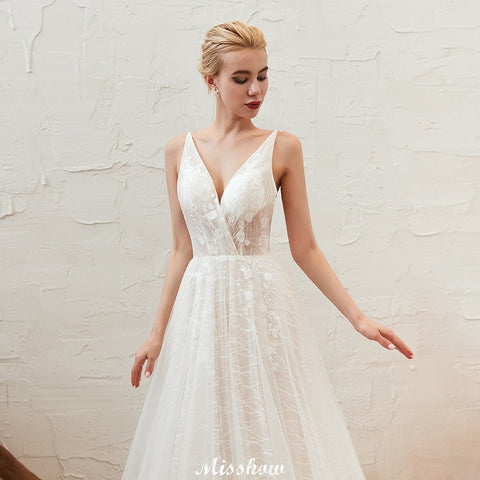 Elegante vestido de novia blanco de tul con escote en V profundo, espalda descubierta y cola de corte.